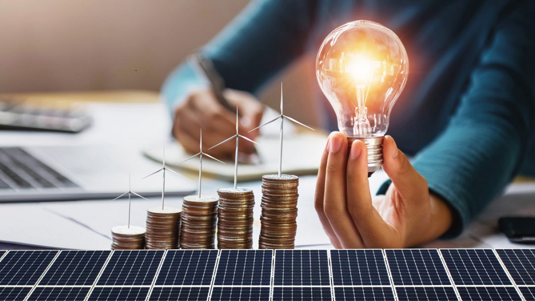 businesswoman holding light bulb with turbine on coins and solar panel. concept saving energy and finance accounting