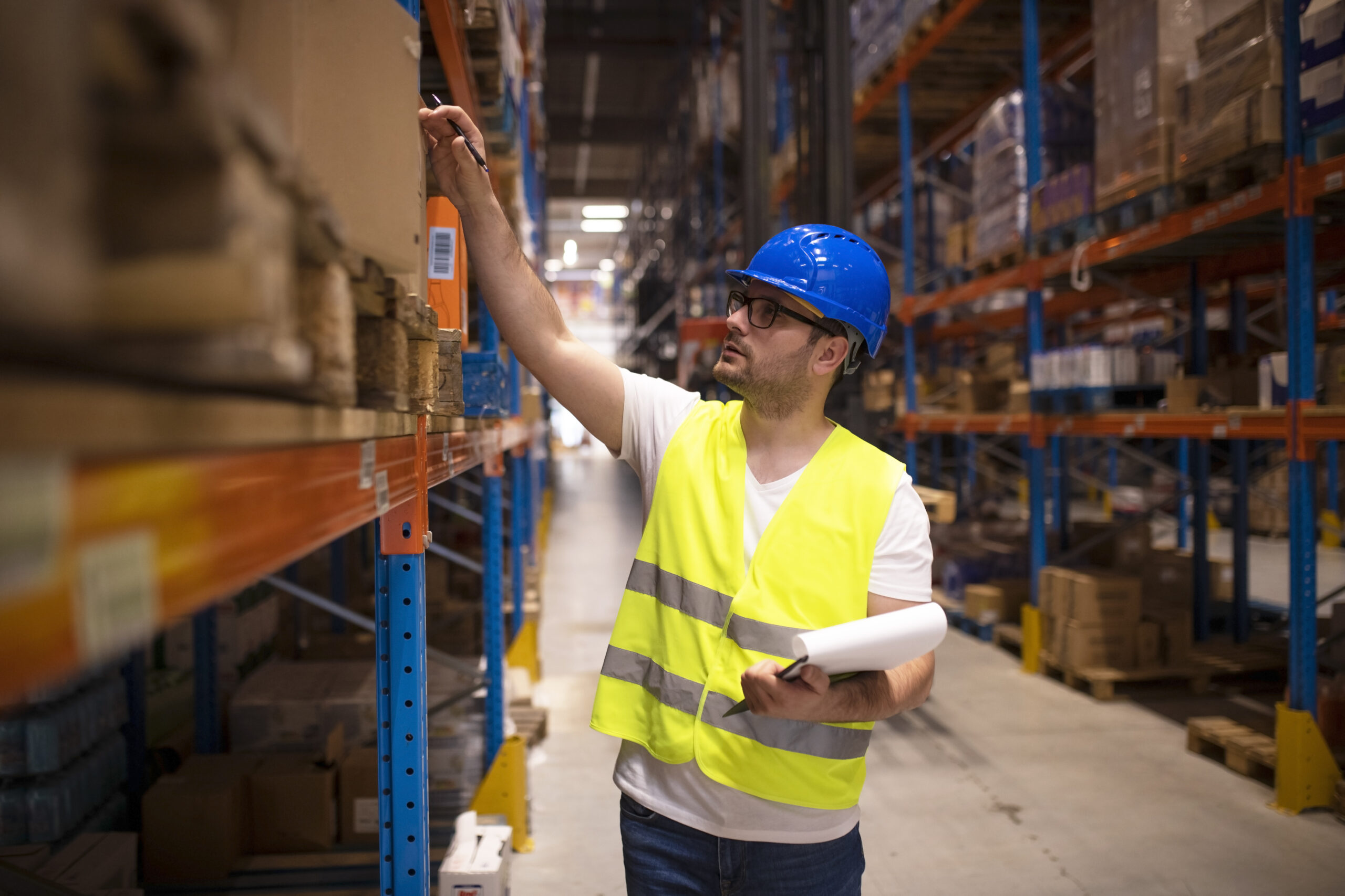 Warehouse worker checking inventory in large distribution warehouse.
