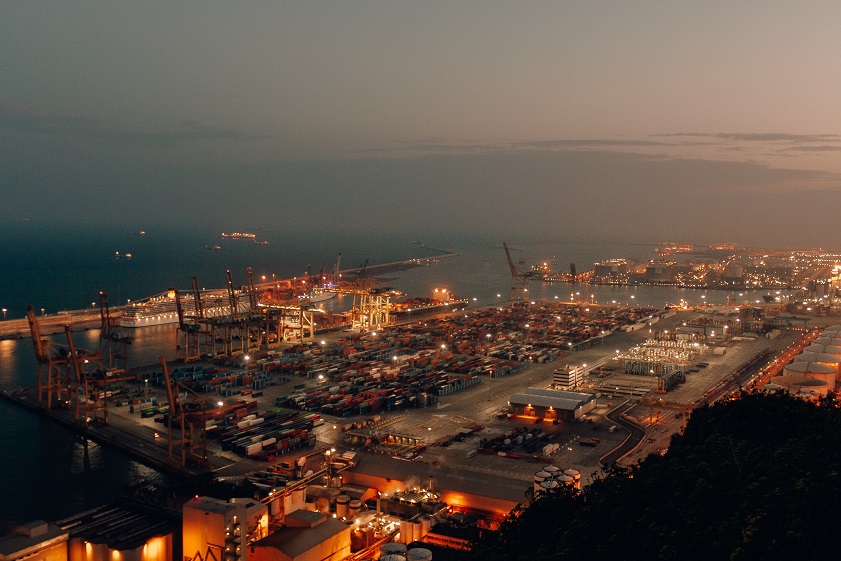 A distant shot of a port with boats loaded with cargo and shipment during nighttime