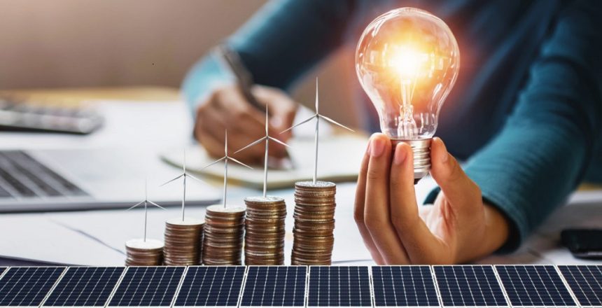 businesswoman holding light bulb with turbine on coins and solar panel. concept saving energy and finance accounting