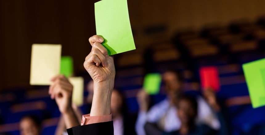 Business executives show their approval by raising hands at conference center