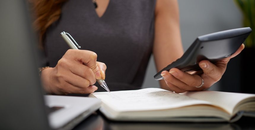 Close-up image of business lady making calculations and taking notes