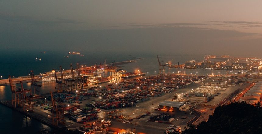 A distant shot of a port with boats loaded with cargo and shipment during nighttime