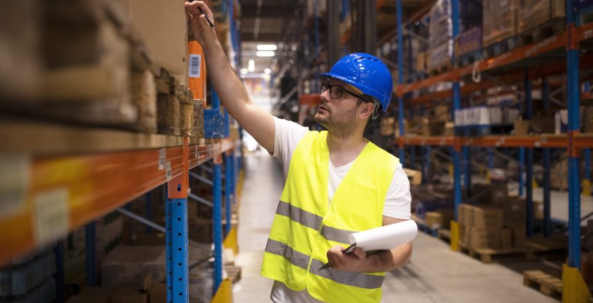 Warehouse worker checking inventory in large distribution warehouse.